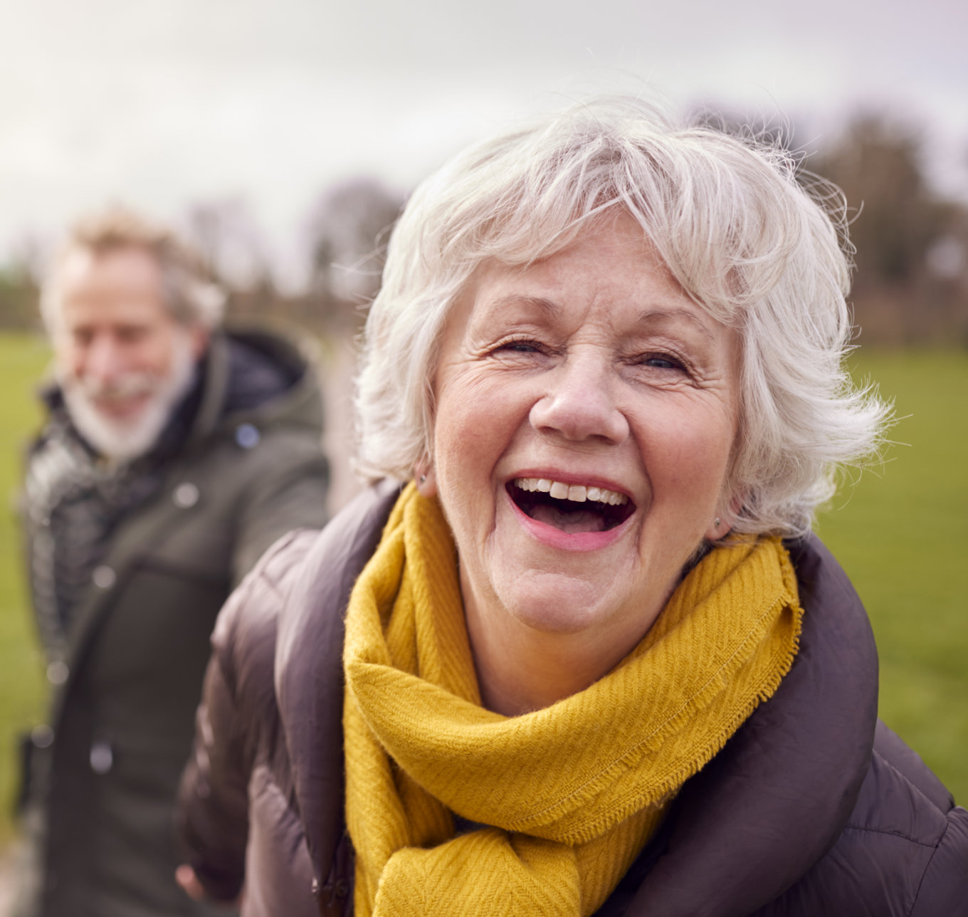 Portrait Of Loving Senior Couple Enjoying Autumn Or Winter Walk Through Park Together