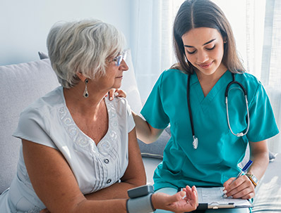 Nurse doing blood pressure monitoring for senior woman at home