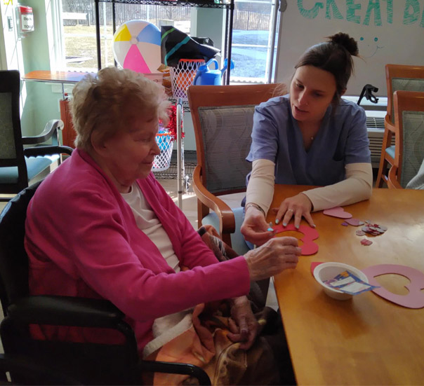 nurse working with senior on crafts