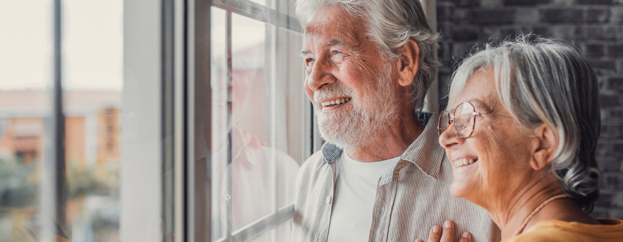 Happy bonding loving middle aged senior retired couple standing near window